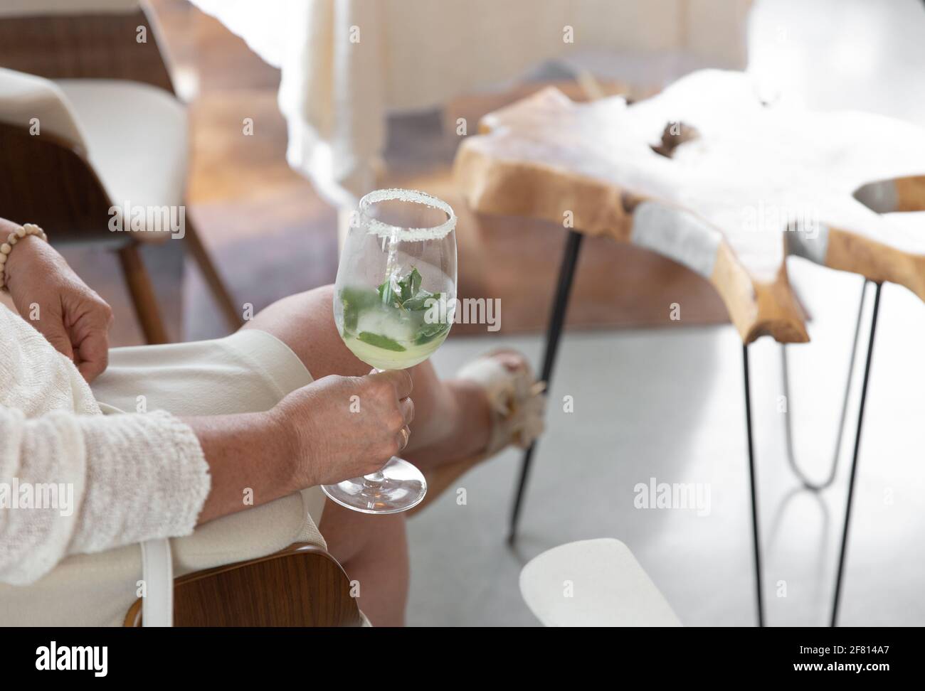 femme assise et tenant une boisson dans un verre Banque D'Images