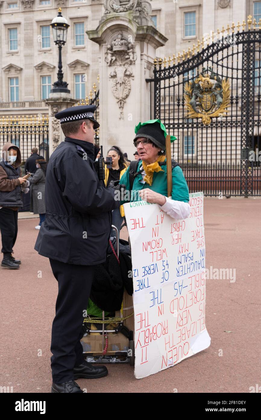 Le garde-fou parle à un démonstrateur vêtu de vert portant un écriteau devant Buckingham Palace, Londres Banque D'Images