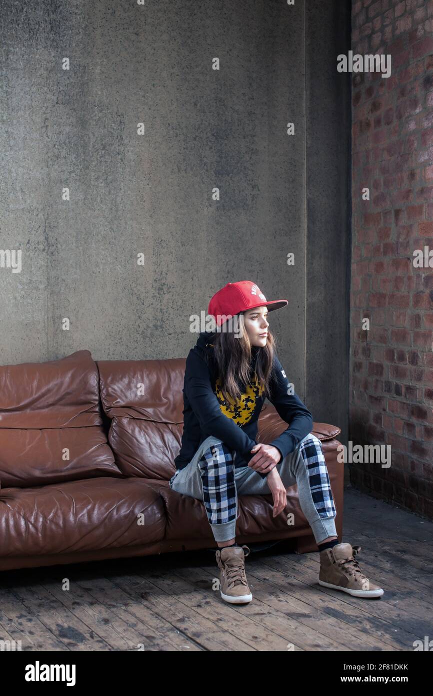Belle jeune femme assise sur un canapé en cuir, regardant rêver dans la distance.prise de vue d'une jeune femme assise sur le canapé . Banque D'Images