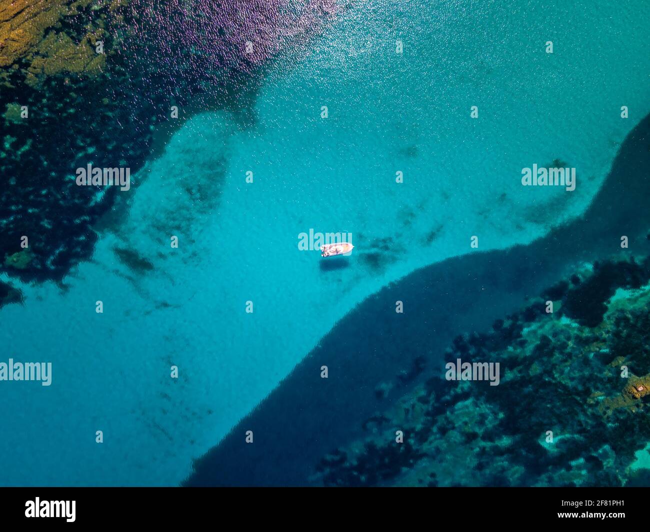 Vue aérienne d'un bateau gonflable rigide amarré dans un Canal turquoise translucide en Méditerranée en Corse Banque D'Images