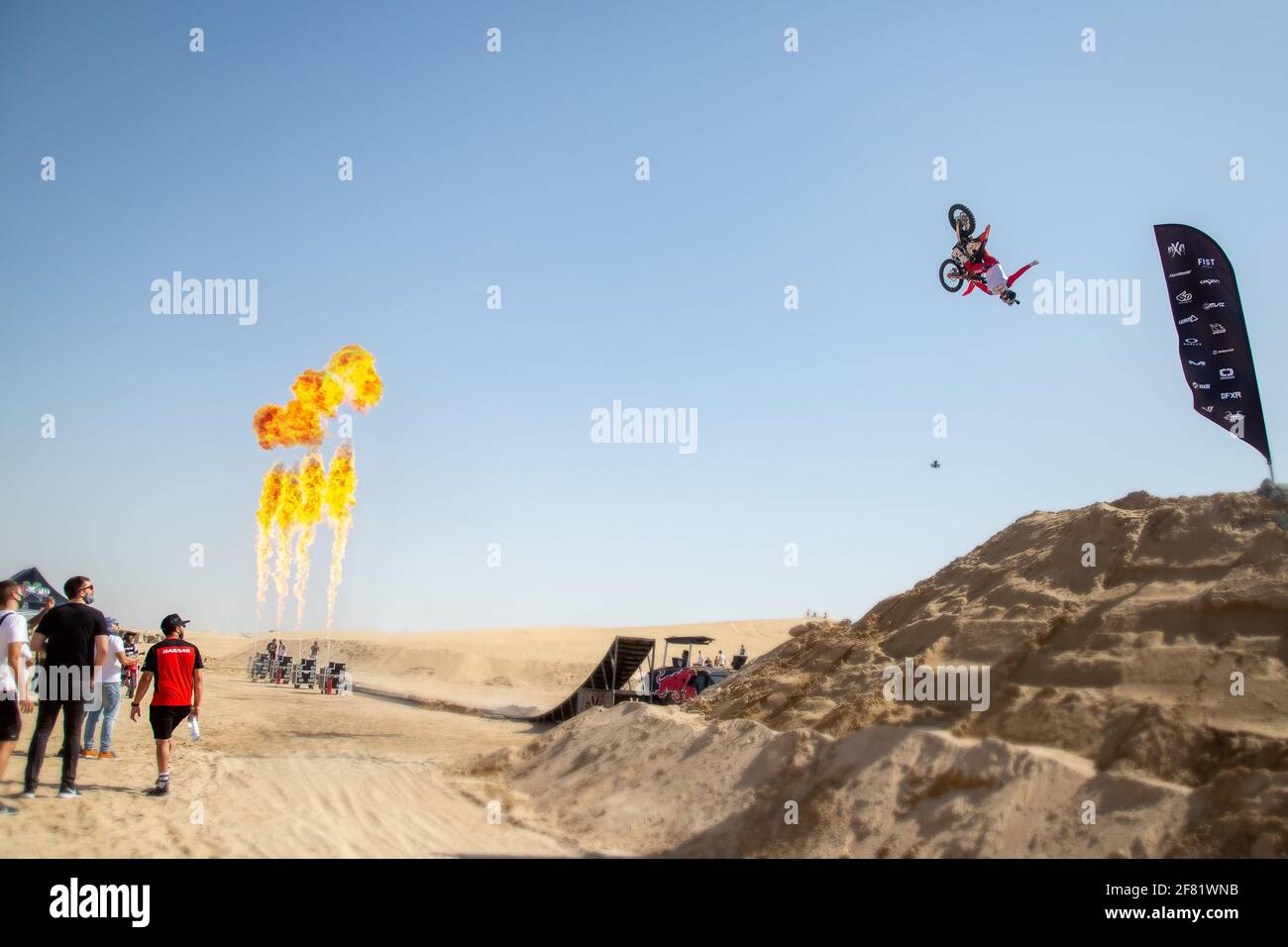 DUBAÏ, ÉMIRATS ARABES UNIS - 31 janvier 2021 : motocross freestyle riders et motos sautant dans le désert avec des dunes et des flammes Banque D'Images