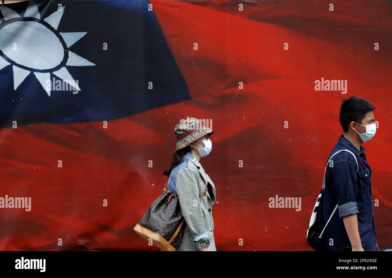 Taipei, Taipei, Taïwan. 11 avril 2021. Les Taiwanais portant un masque facial marchent au-delà d'une immense bannière avec un drapeau national de Taiwan dans un contexte de tensions accrues avec la Chine. Avec l'envoi de nouveaux avions de chasse à Pékin sur l'île, le ministre des Affaires étrangères de Taïwan, Joseph Wu, a déclaré que Taiwan se défendra au « très dernier jour » tout en favorisant les relations avec les États-Unis sur les domaines militaire, économique, technologique et médical. Crédit : Daniel CEng Shou-Yi/ZUMA Wire/Alay Live News Banque D'Images