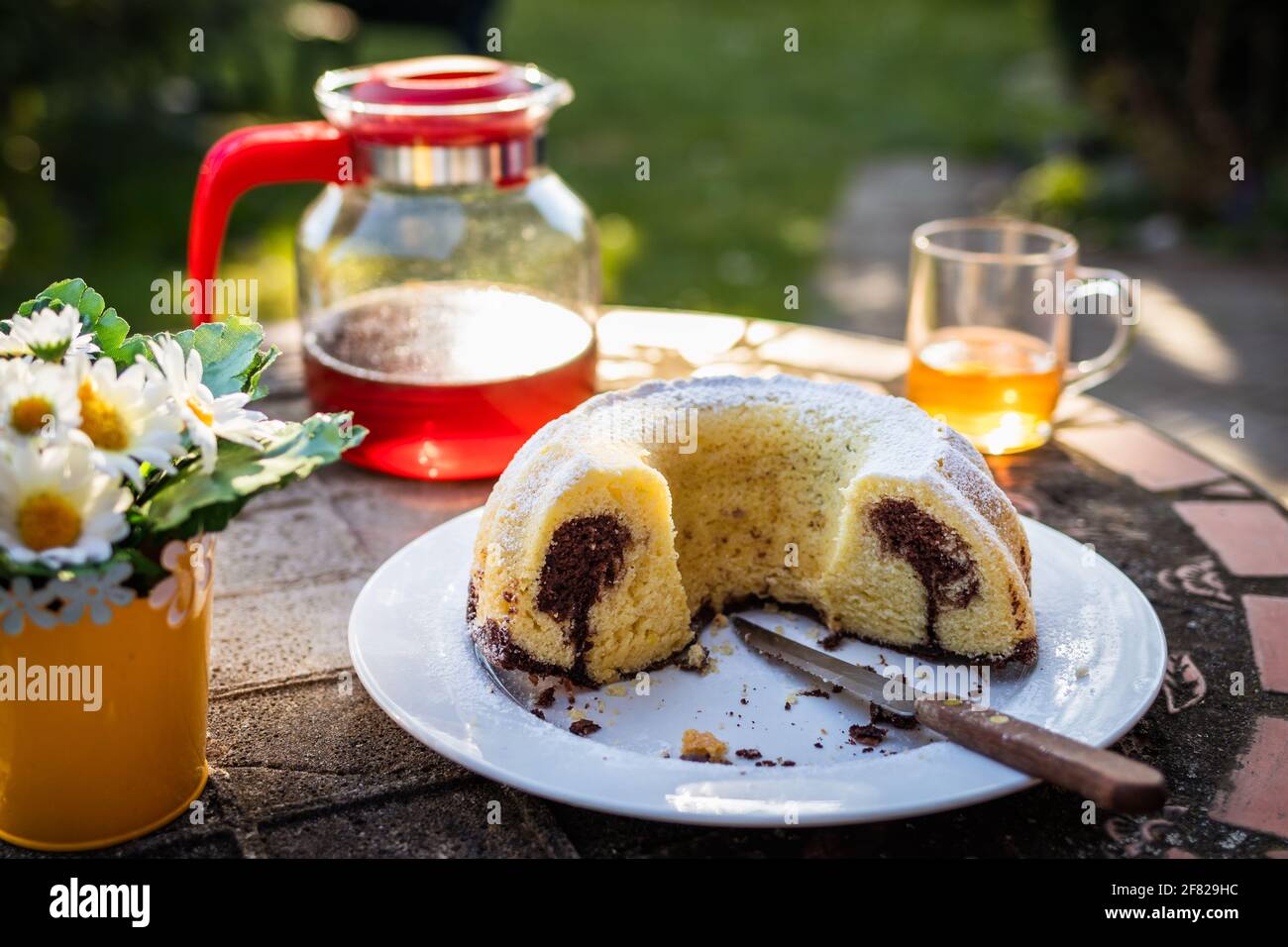 Petit gâteau en marbre et thé sur une table dans le jardin. On y sert des mets sucrés et des boissons chaudes à l'extérieur Banque D'Images