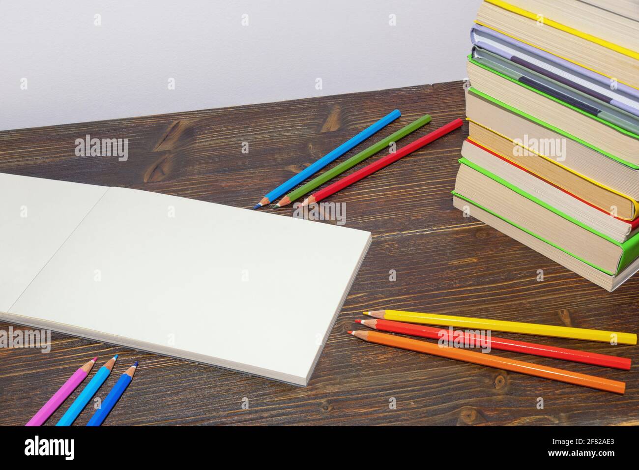 Crayons de couleur, livres et croquis ouverts sur table rustique sombre. Espace libre pour le texte ou l'image Banque D'Images