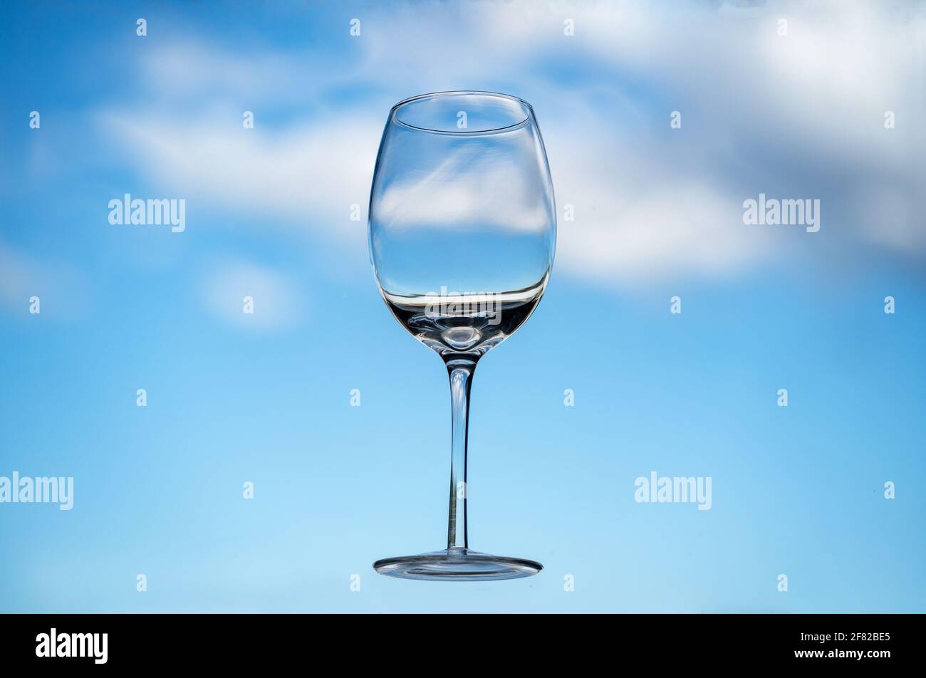 Verre à vin flottant vide devant un ciel bleu avec des nuages moelleux  Photo Stock - Alamy
