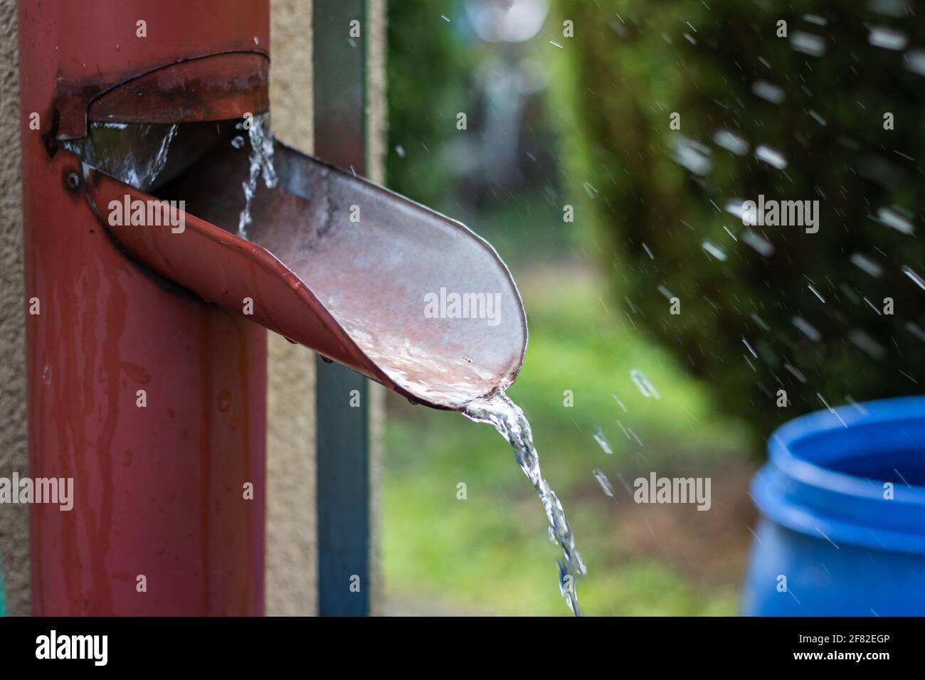 L'eau de pluie s'écoulant du toit s'écoule dans le tonneau du jardin. Gouttes de pluie dans le flou de mouvement. L'aluminium se prépare sous la pluie. Style de vie durable dans le jardin Banque D'Images