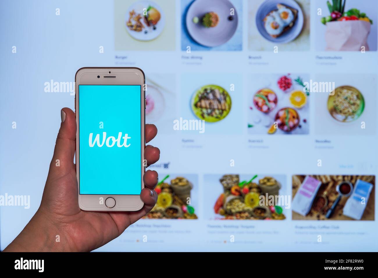 Wolt concept de commande de livraison de nourriture. Les femmes tient la main avant l'écran de téléphone mobile avec le logo de l'entreprise de finition et la page Web avec les partenaires de la plate-forme de restaurant Banque D'Images