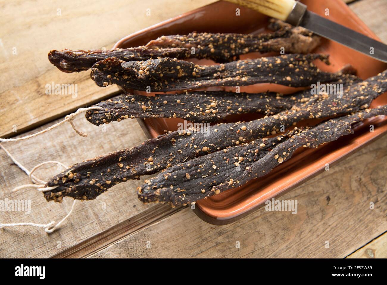 Des bandes de bœuf britannique provenant d'un joint de torréfaction qui ont été séchées à l'air à la maison pour faire du biltong avec du sel, du sucre, du vinaigre brun et des épices y compris le co Banque D'Images