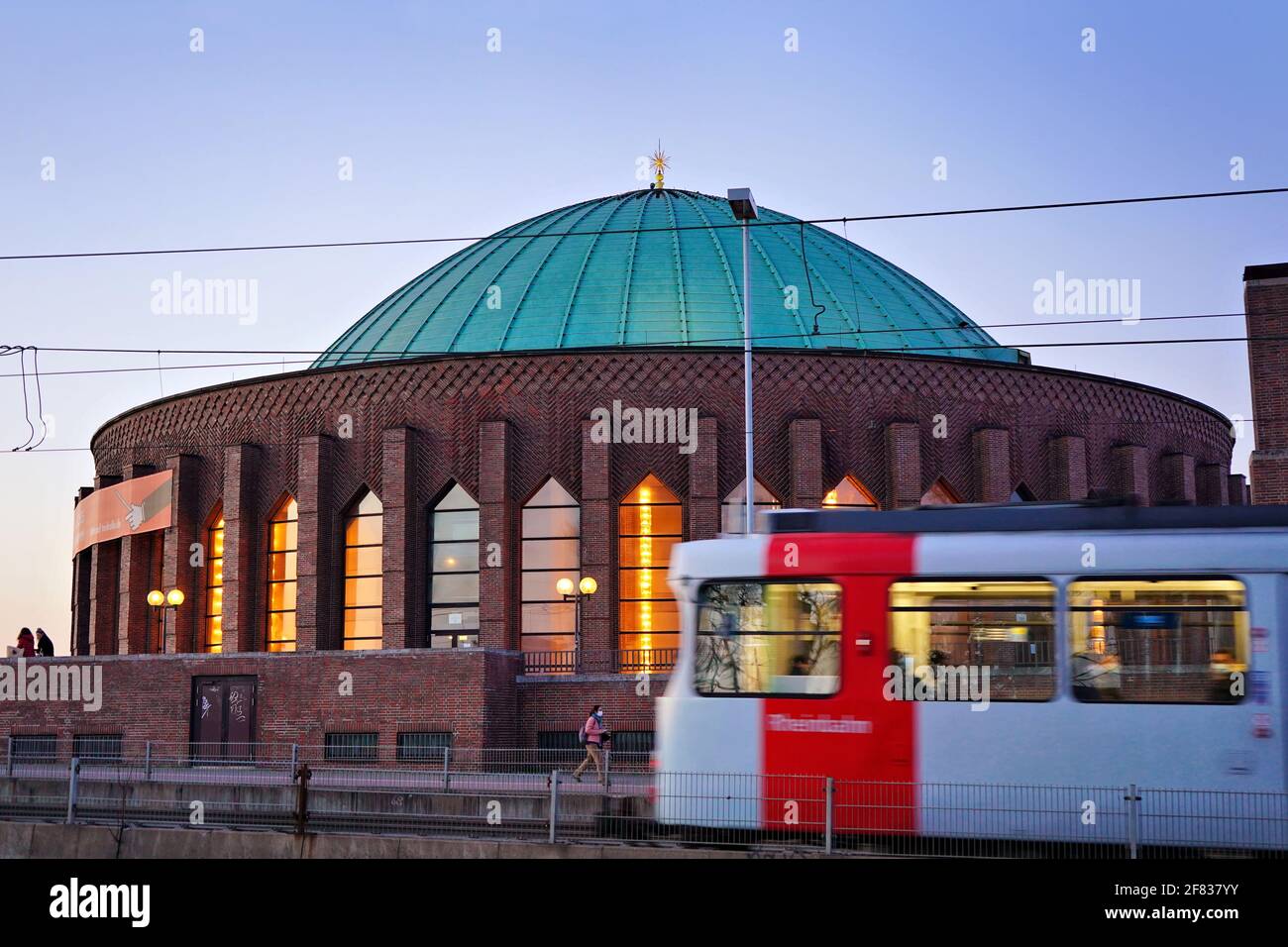 La salle de concert illuminée Tonhalle, située au bord du Rhin, avec un tramway flou. La salle de concert a été construite en 1925/26. Banque D'Images