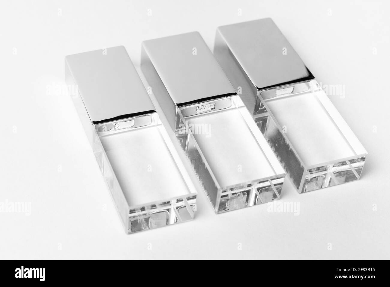 Trois clés USB en verre transparent avec couvercle en métal sur fond gris. Mise en page. Gros plan. Copier l'espace. Une haute résolution. Banque D'Images