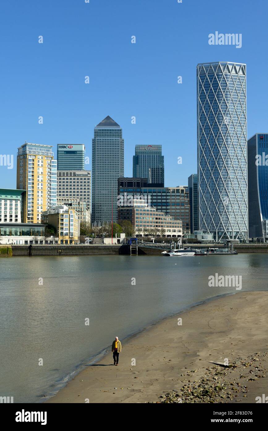 Homme marchant sur la plage marémotrice, Canary Wharf Estate, Docklands, Thames Riverside, East London, Royaume-Uni Banque D'Images