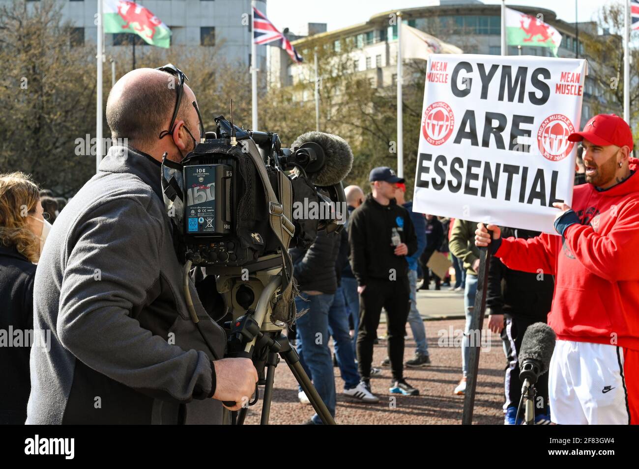 Cardiff, pays de Galles - avril 2021 : l'équipe de caméras de télévision filme et interviewe une personne avec un grand panneau lors d'une manifestation contre le verrouillage des gymnases. Banque D'Images