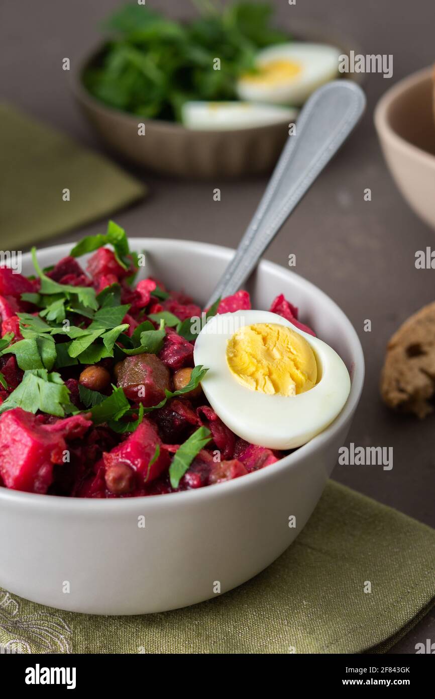 Vinaigrette russe à salade dans des assiettes avec œufs durs et pain noir, salade de légumes durs et marinés et pois verts en conserve Banque D'Images