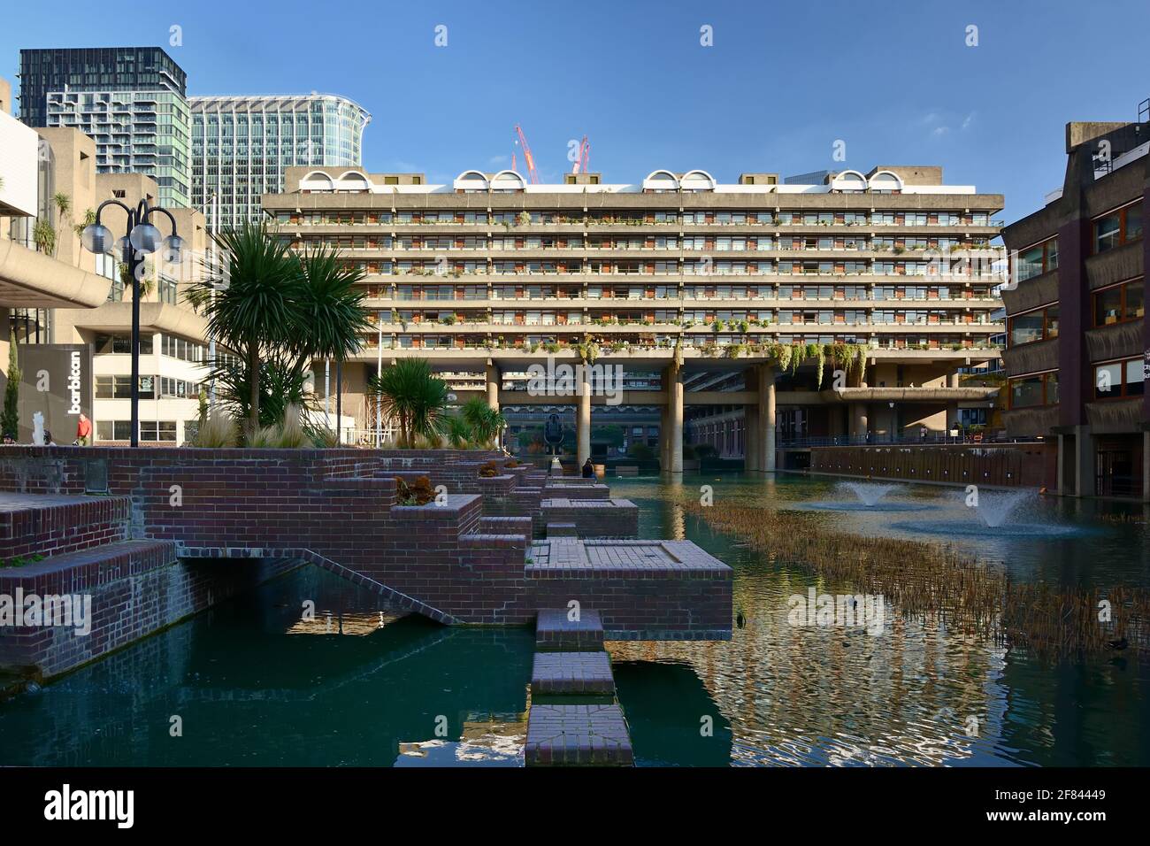 Le Barbican Center, Lakeside terrasse fontaines avec l'un des blocs résidentiels de Barbican Estate en arrière-plan, ville de Londres, Royaume-Uni Banque D'Images