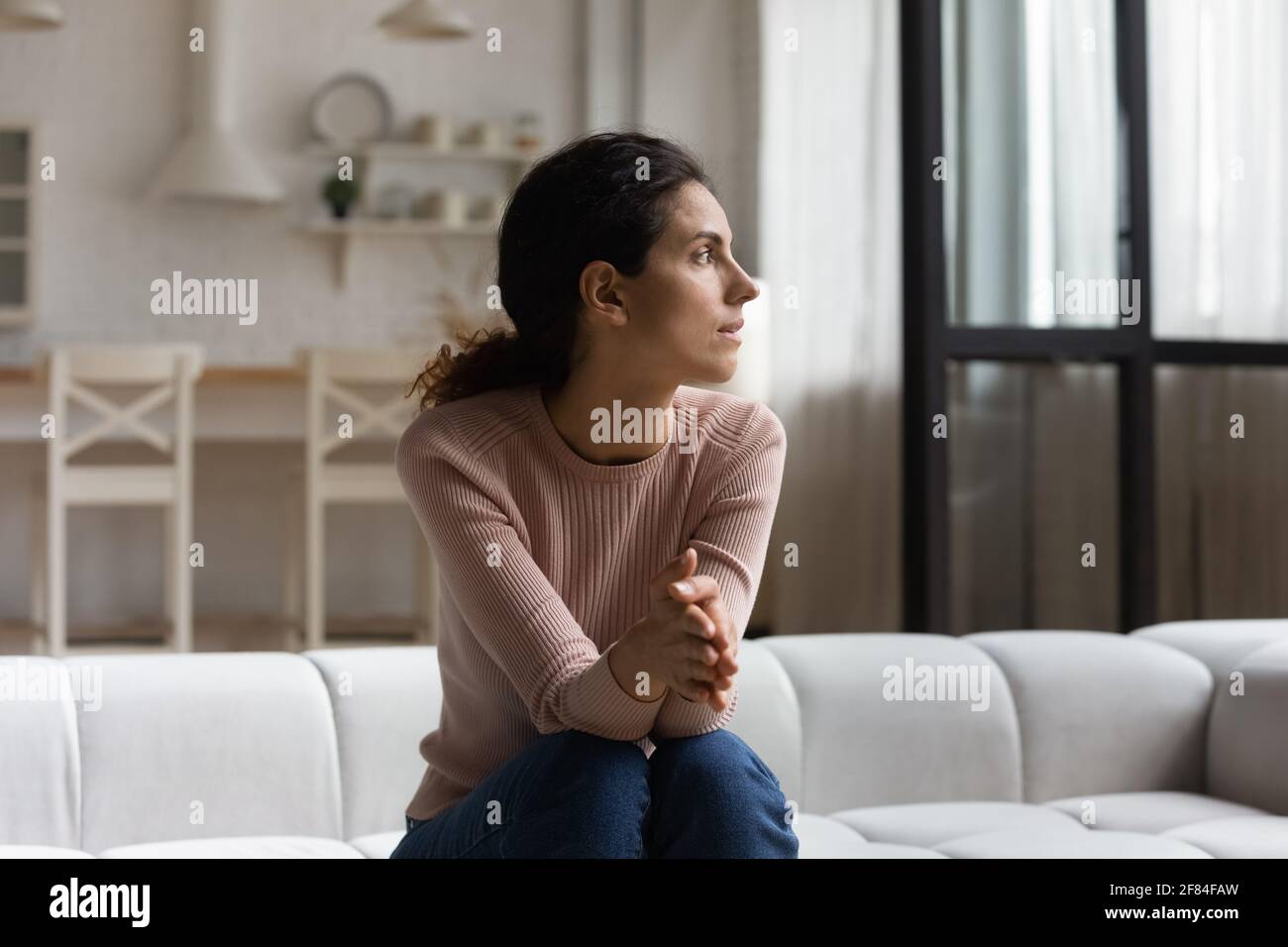 Une femme hispanique inquiète et s'assoit sur un canapé. Attendez-vous à ce qu'elle soit un client important Banque D'Images