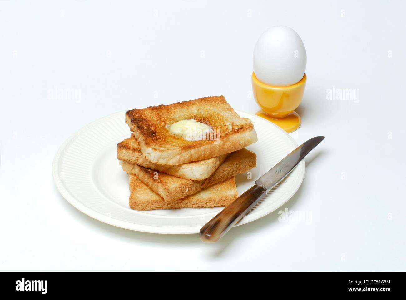 Toasts, beurre fondu, œuf de petit déjeuner, toasts, assiette, couteau, coquetier, œuf Banque D'Images