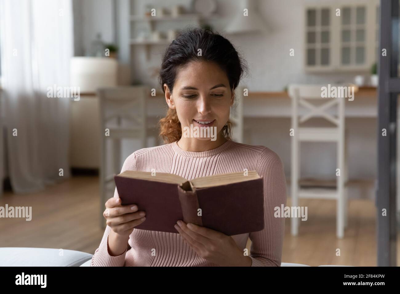 Une femme hispanique intelligente a lu un vieux volume de littérature classique dans l'antiquaire Banque D'Images