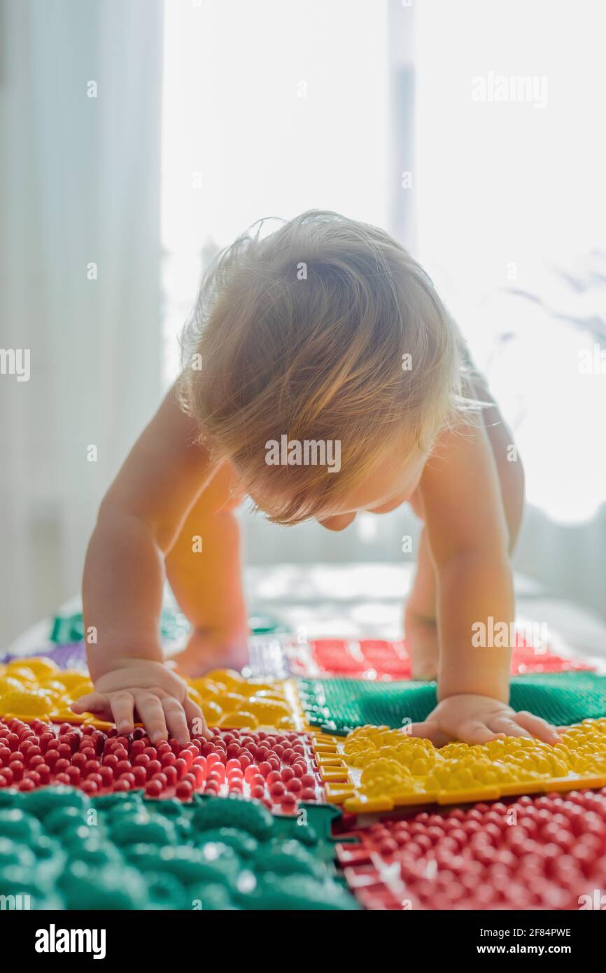 L'enfant marche pieds nus sur des tapis de massage multicolores. Massage des pieds Banque D'Images