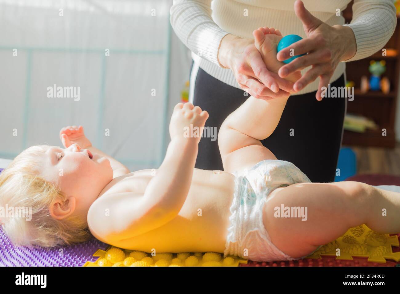 Maman Donne Au Bebe Un Massage Des Pieds Avec Des Boules De Massage Gros Plan Photo Stock Alamy
