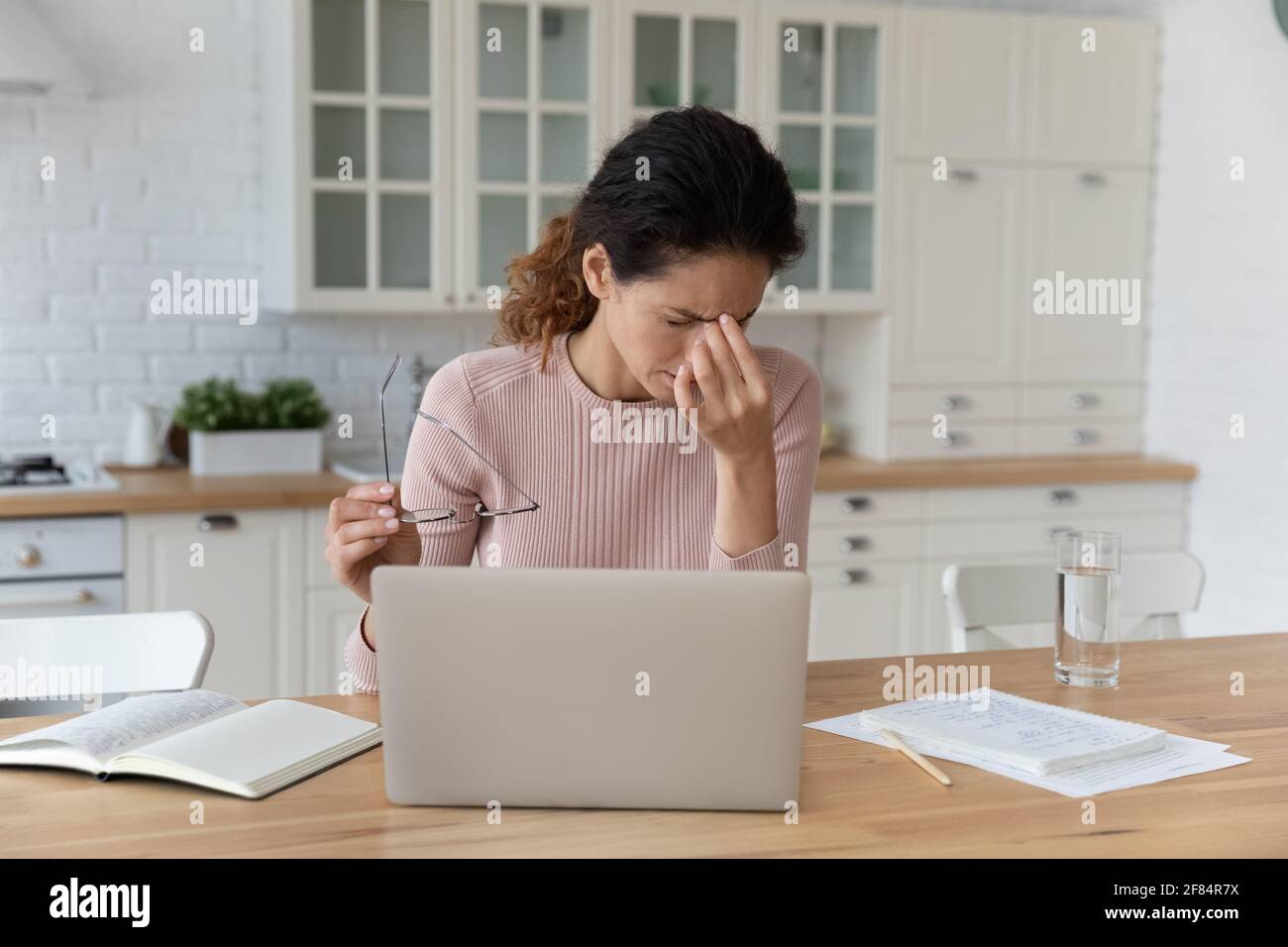 Jeune femme latines fatiguée distraite du pont de nez de frottement d'ordinateur portable Banque D'Images
