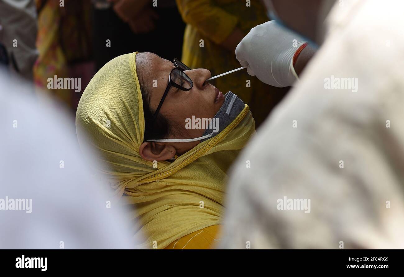 Prayagraj, Inde. 11 avril 2021. Le 11 avril 2021, un agent de santé a recueilli un écouvillon auprès d'une femme à Prayagraj, dans l'État d'Uttar Pradesh, dans le nord de l'Inde. L'Inde a signalé un record de 152,879 nouveaux cas de COVID-19 dimanche, portant le total à 13,358,805, selon les données publiées par le gouvernement fédéral. Credit: STR/Xinhua/Alay Live News Banque D'Images