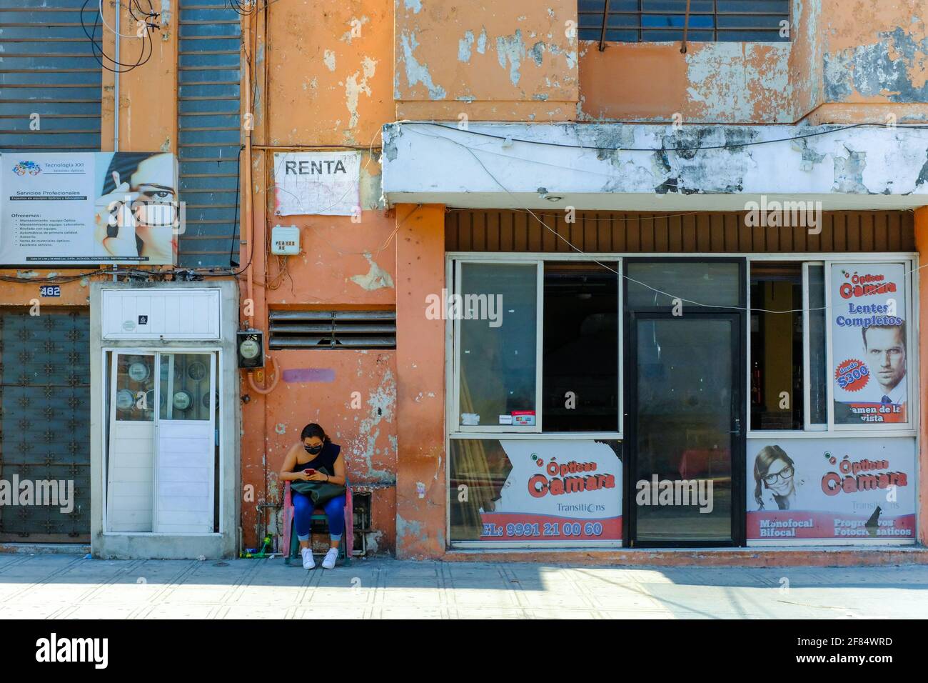 Femme se reposant sur une rue décadée dans le Centro Historico Merida Mexico. L'ancien centre a été particulièrement touché par les effets économiques de la pandémie Covid-19 Banque D'Images