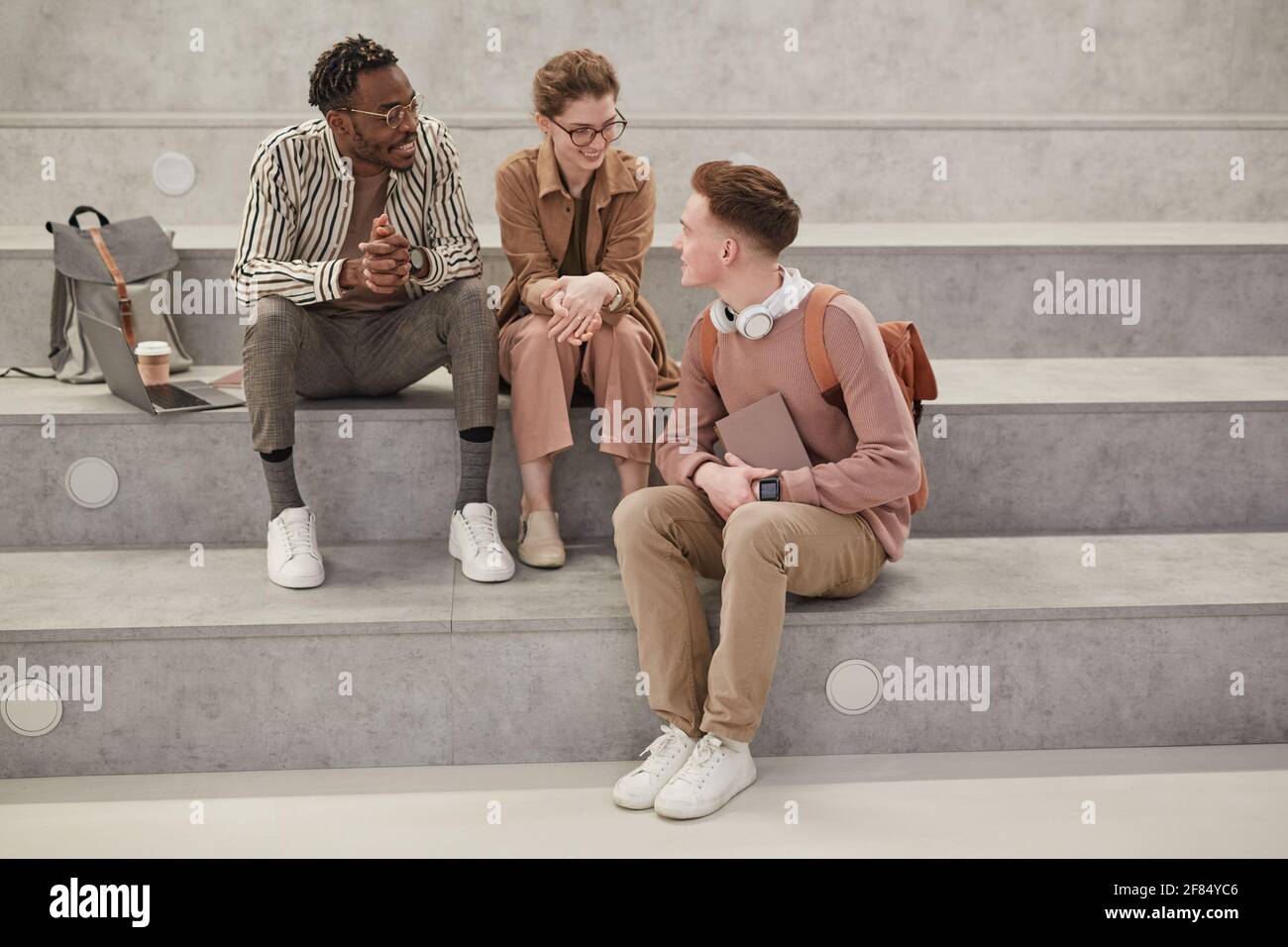 Portrait complet de trois étudiants discutant pendant la pause dans le salon universitaire moderne, espace de copie Banque D'Images