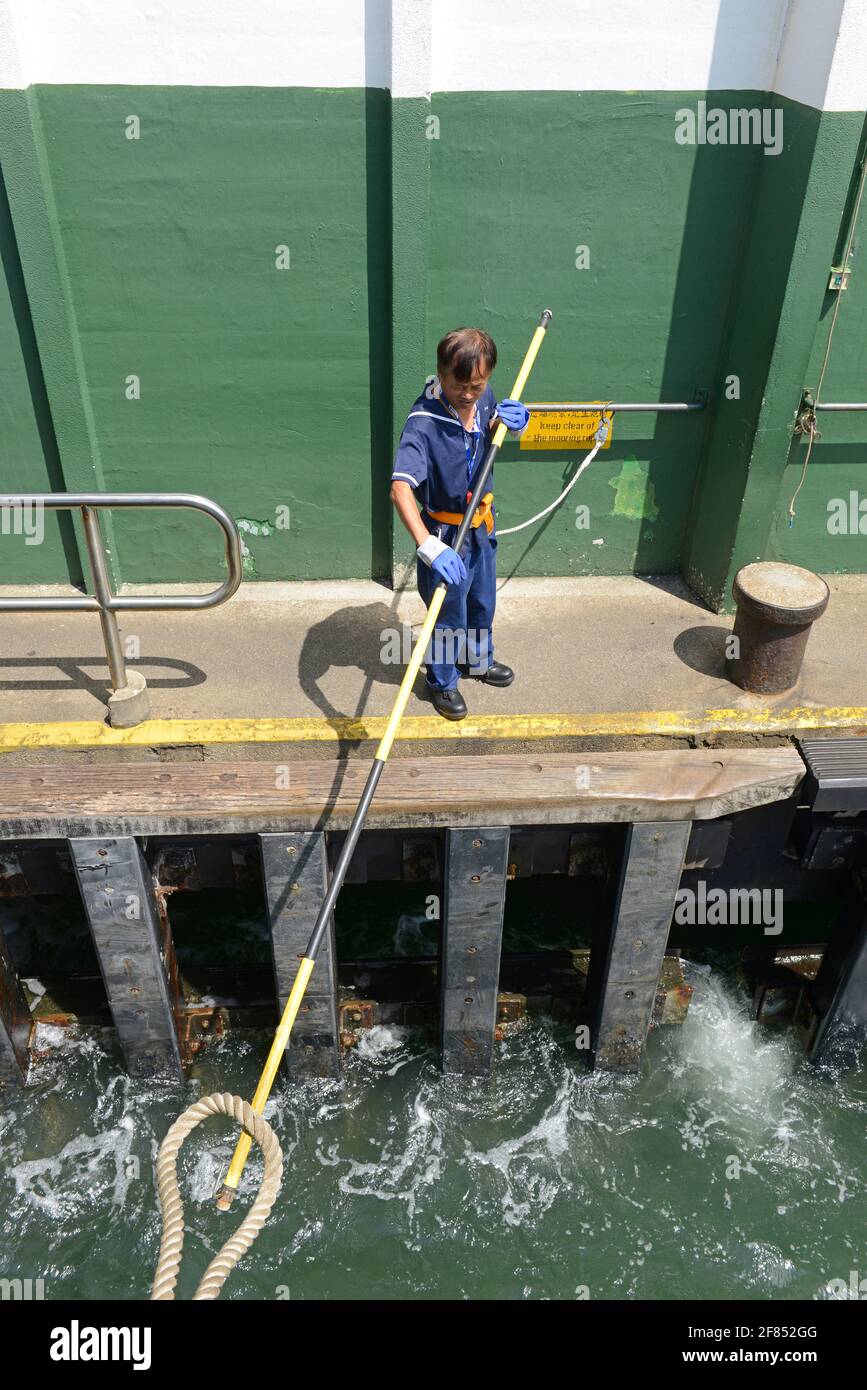 Un employé de quai attrape la corde d'amarrage d'un Star Ferry alors qu'il se prépare à se mettre à quai au terminal de ferry central, Hong Kong, Chine Banque D'Images