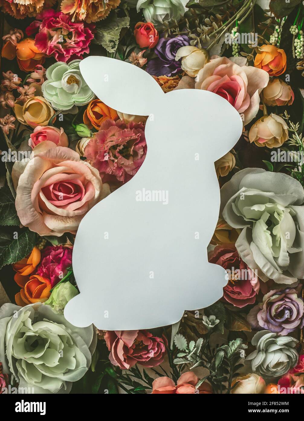 Carte de vœux en forme de lapin sur des fleurs colorées ; vue du dessus, pose à plat ; arrière-plan de printemps ou de Pâques créatif minimal avec espace de copie Banque D'Images