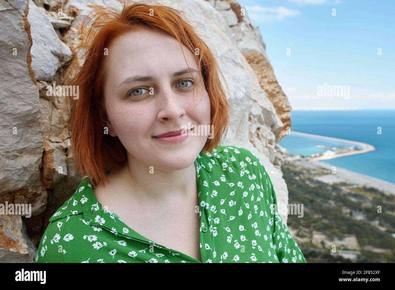 Portrait d'une jeune femme caucasienne à tête rouge près d'une falaise au-dessus de la mer à Antalya au printemps. Banque D'Images