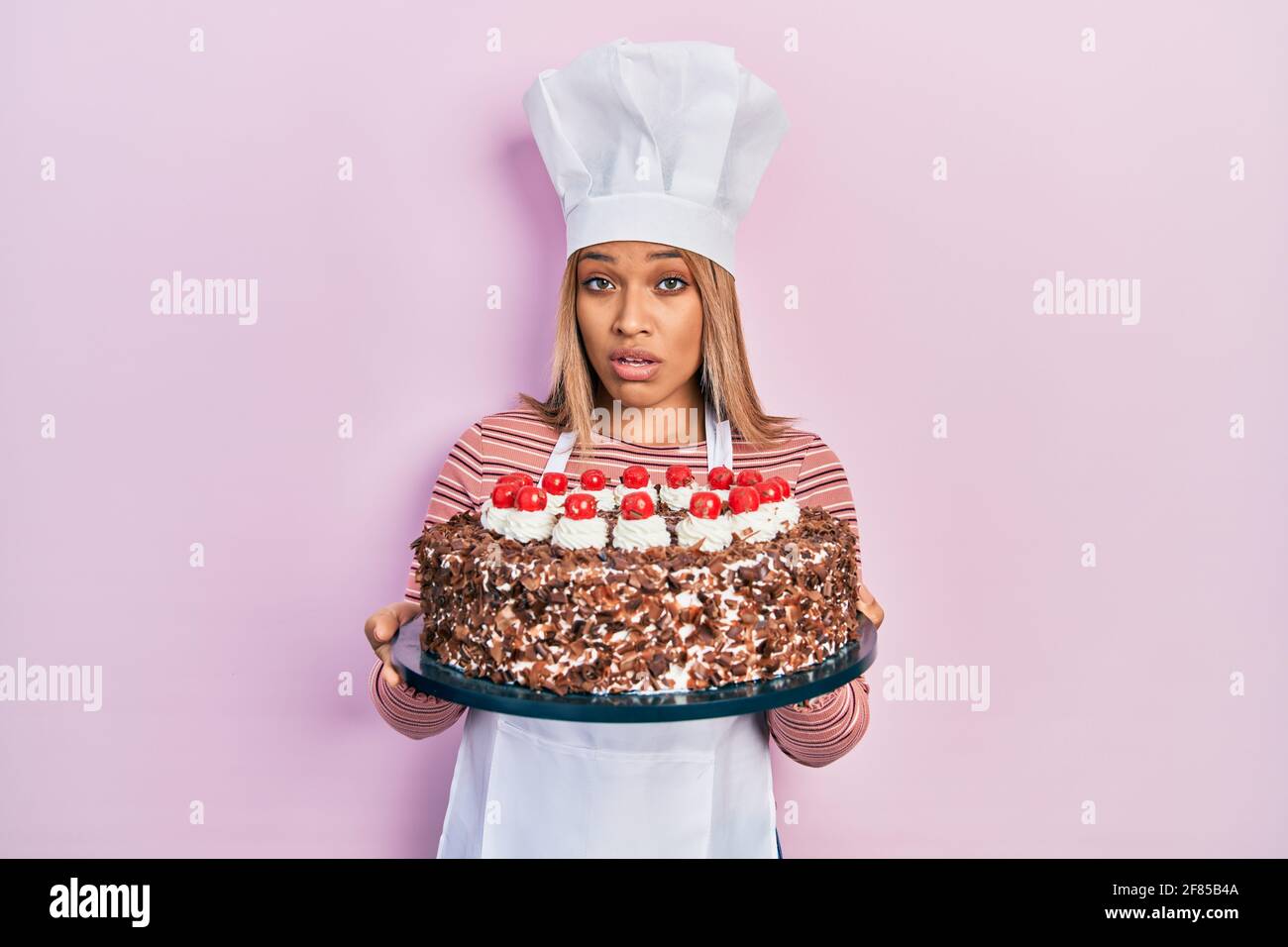 Belle Femme Hispanique Portant Uniforme De Cuisinier Et Chapeau Et Gateau D Anniversaire Dans Le Visage De Choc Regardant Sceptique Et Sarcastique Surpris Par La Bouche Ouverte Photo Stock Alamy