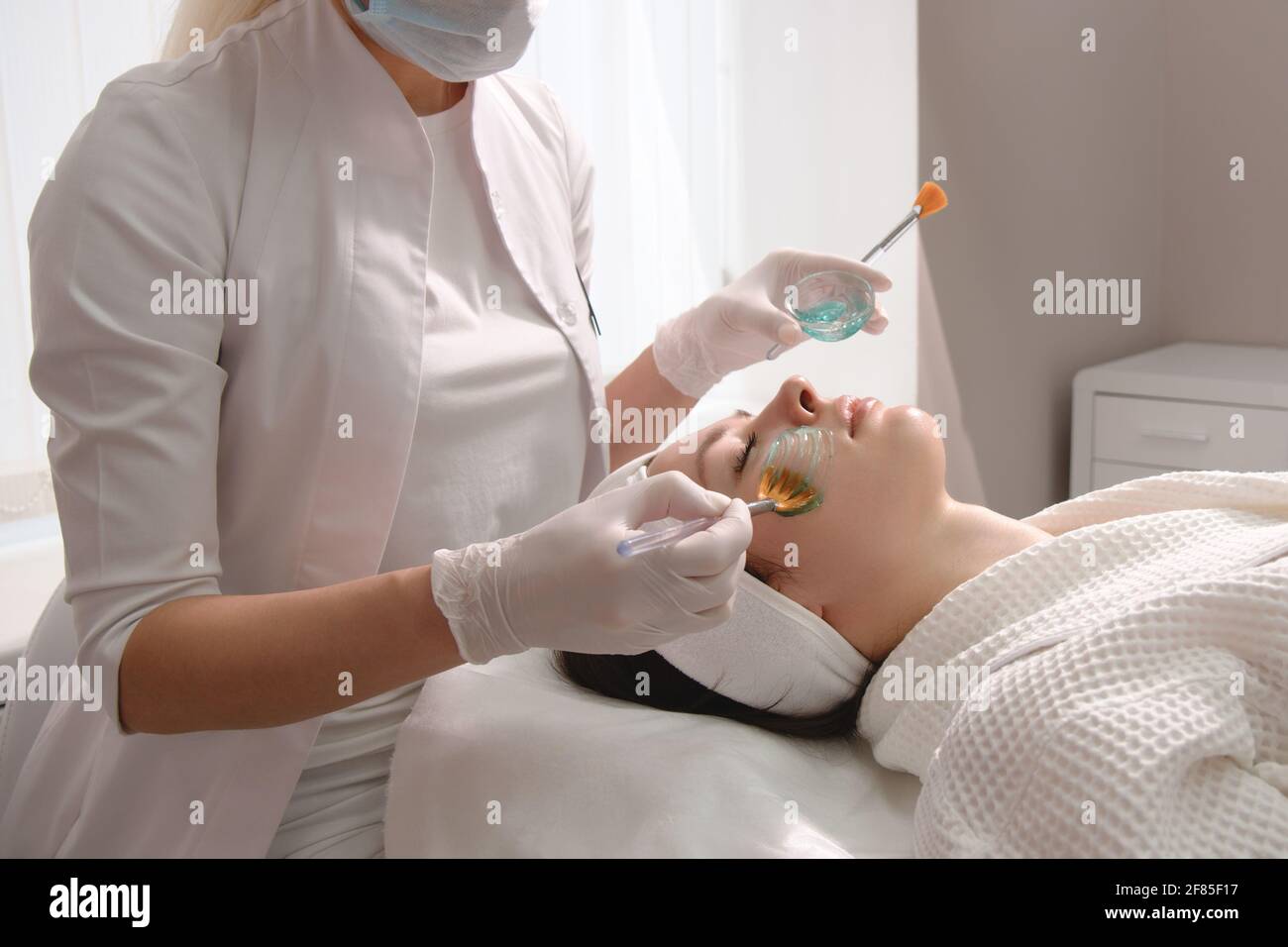 Soin du visage. Un masque est appliqué au visage d'une femme dans une clinique de cosmétologie. Gros plan Banque D'Images