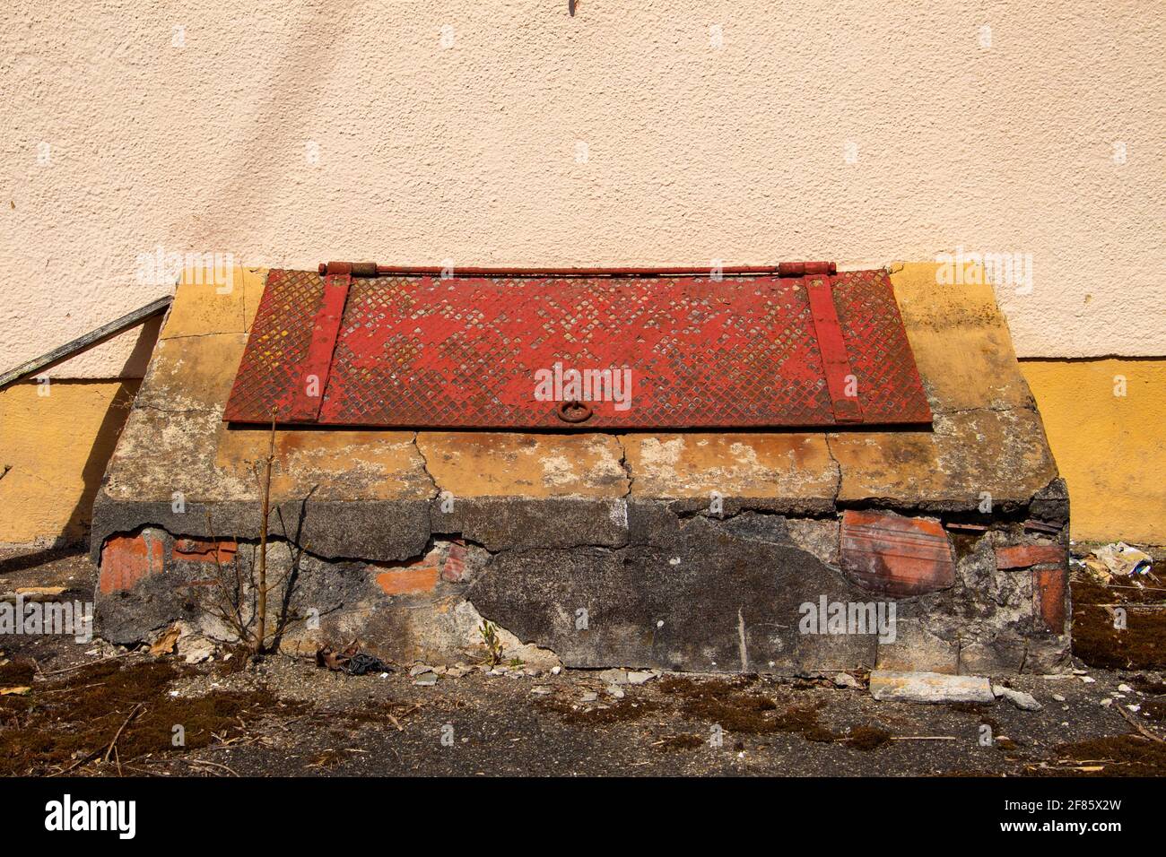 Ancien couvercle en acier abîmé par-dessus une trappe à l'avant de un mur d'un bâtiment Banque D'Images