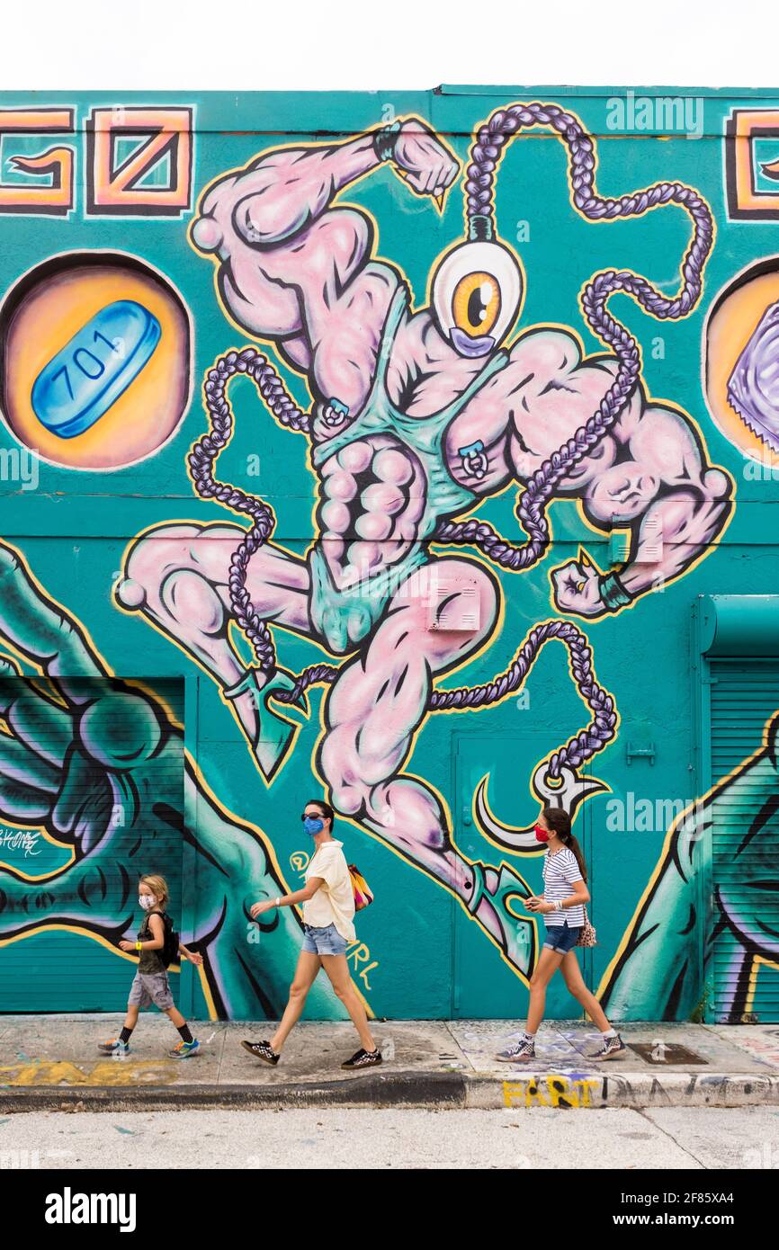 Une famille marche près d'un mur couvert de graffiti dans le quartier artistique de Wynwood, Miami, Floride, États-Unis Banque D'Images