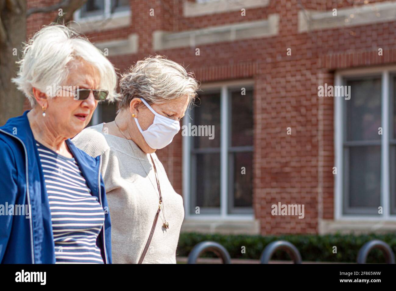 Frederick, Maryland États-Unis 04-07-2021: Deux femmes caucasiennes âgées marchent à l'extérieur lors d'une journée ensoleillée pendant la pandémie de COVID 19. On porte un masque facial bu Banque D'Images