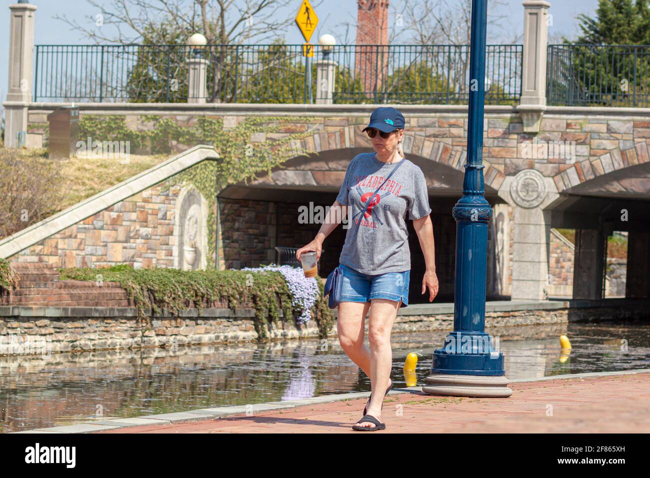 Frederick, MD, USA 04-07-2021: Une femme d'âge moyen de race blanche portant des vêtements décontractés d'été marche seule dans le parc Carroll Creek, dans le centre-ville de Frederi Banque D'Images