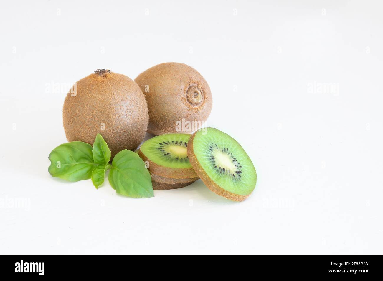 Kiwis entiers et en demi-fruits frais isolés sur fond blanc avec espace de texte Banque D'Images