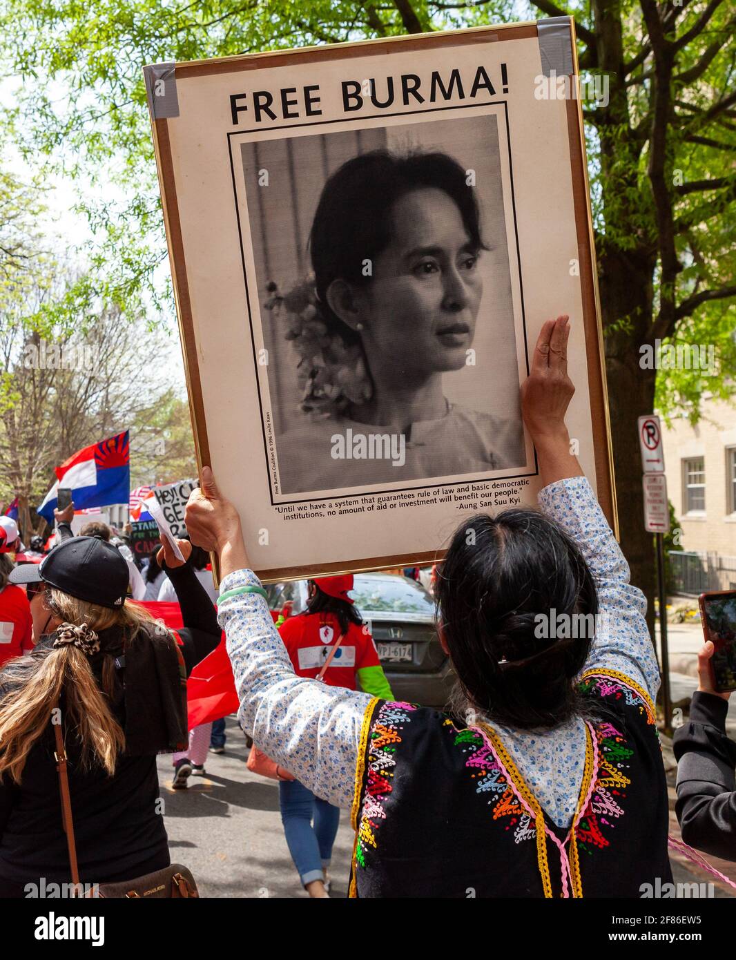 Un manifestant porte une grande photo encadrée d'Aung San Suu Kyi et soulève trois doigts lors d'une marche contre le coup d'État militaire au Myanmar. Banque D'Images