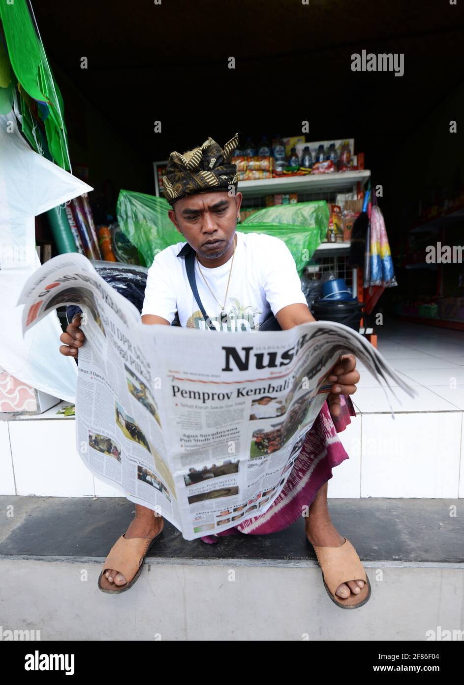 Un homme balinais lisant le journal à Ubud, Bali. Banque D'Images