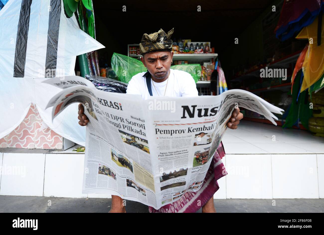 Un homme balinais lisant le journal à Ubud, Bali. Banque D'Images