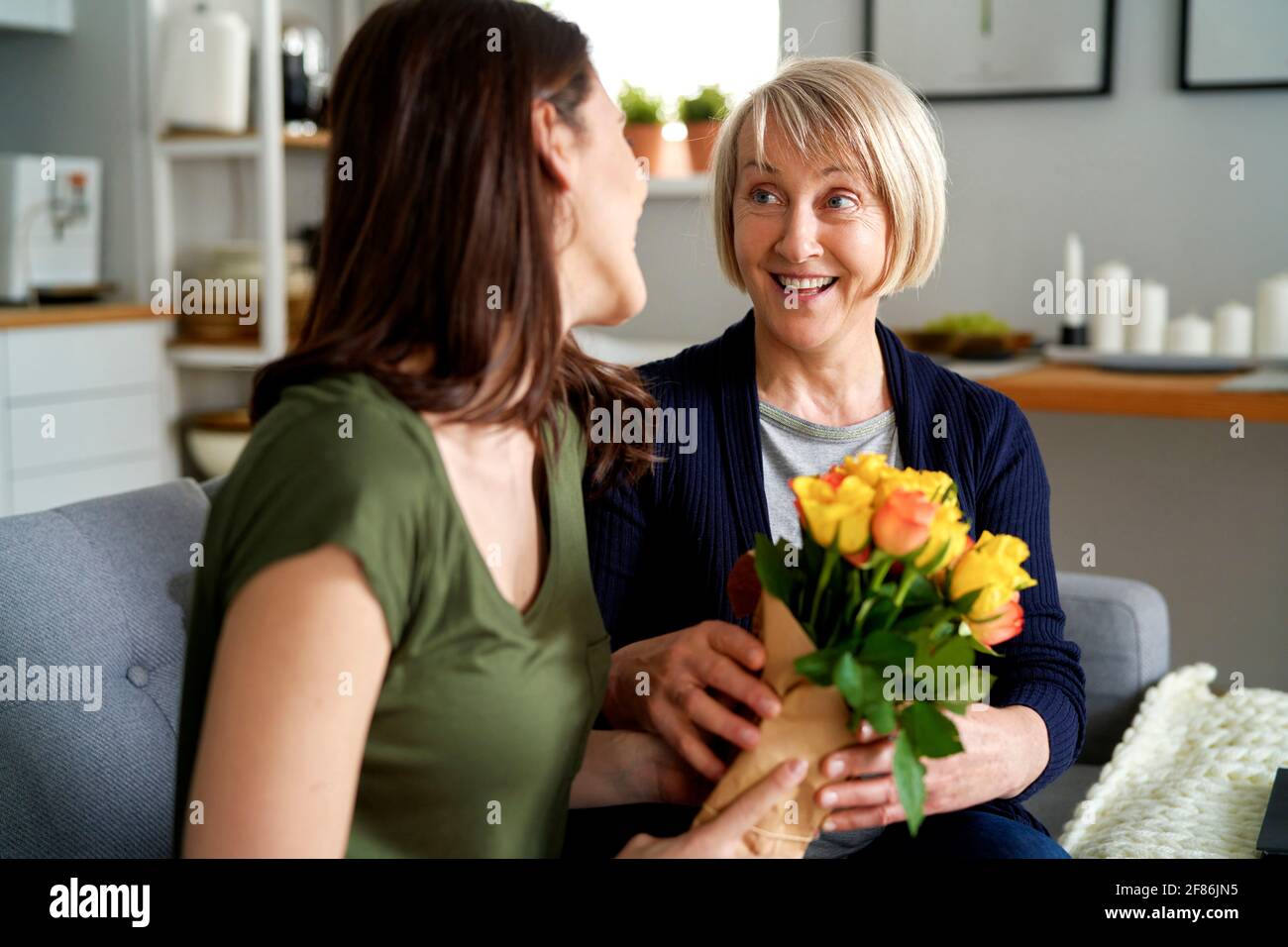 La mère surprise reçoit un bouquet de fleurs de la fille adulte Banque D'Images