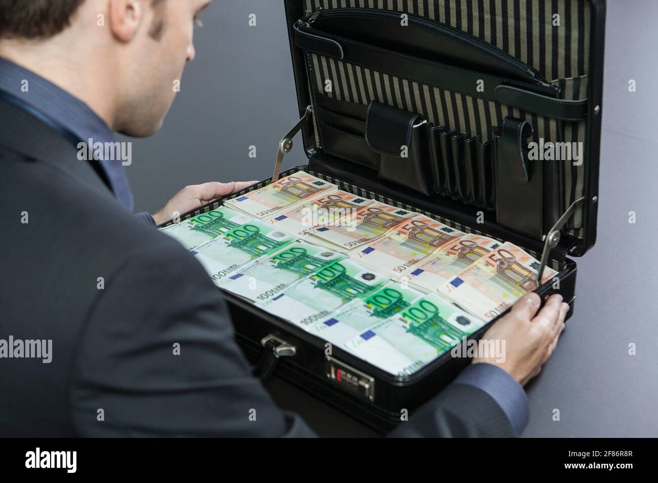 Homme d'affaires regardant un porte-documents plein d'euros Banque D'Images