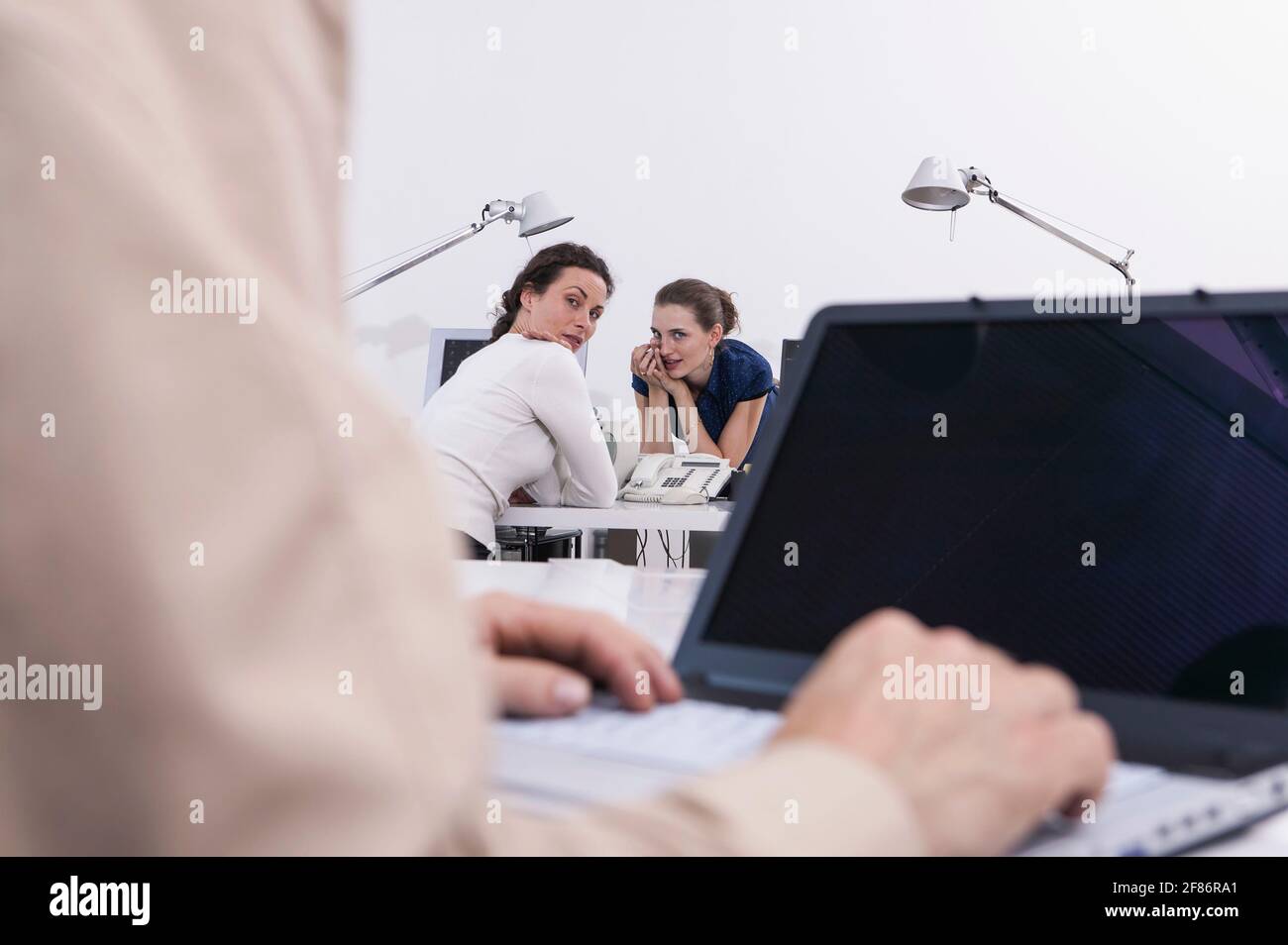 Les femmes d'affaires commet des potins sur leurs collègues au bureau Banque D'Images