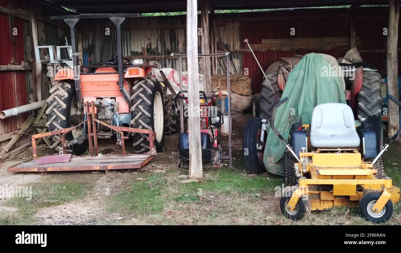 Million Creek NSW 2800, Australie. Garage de la maison du vieux village .deux tracteurs et propriétaires de pelouse. Banque D'Images