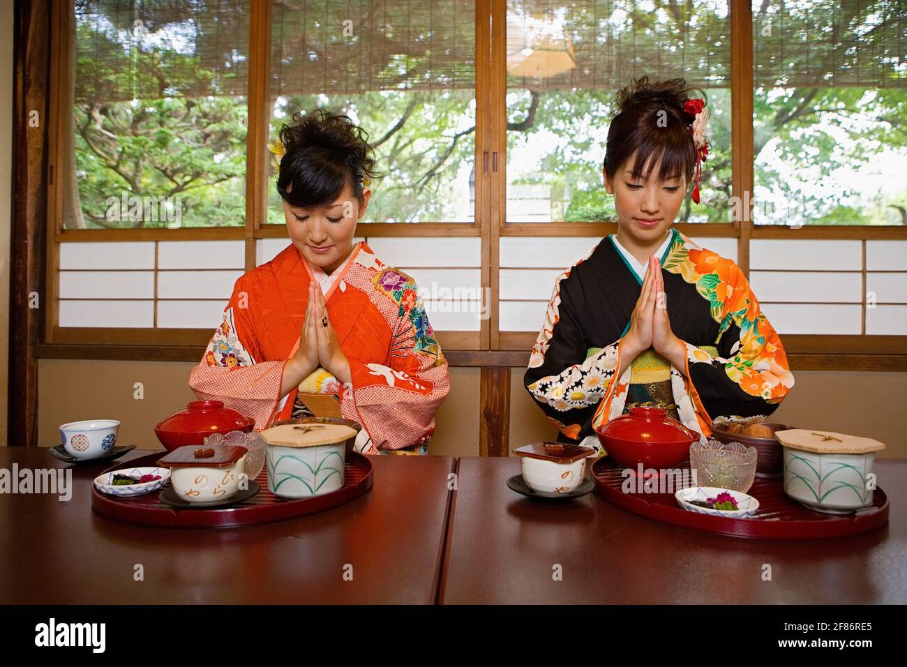 Les jeunes femmes des kimonos prient pour le déjeuner au restaurant Banque D'Images