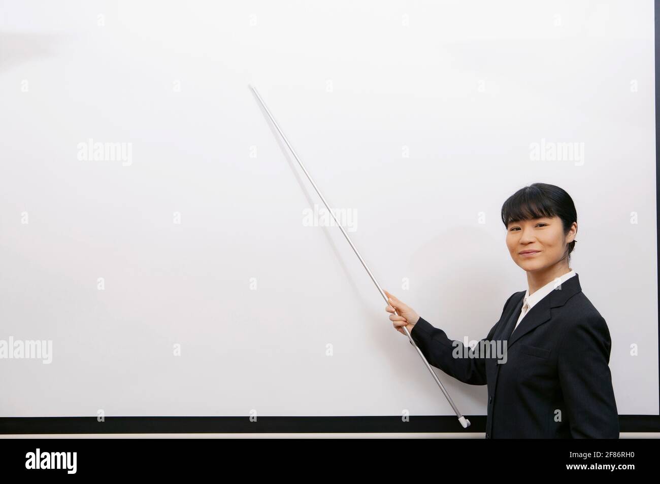 Portrait d'une femme d'affaires confiante avec pointeur sur le tableau blanc Banque D'Images