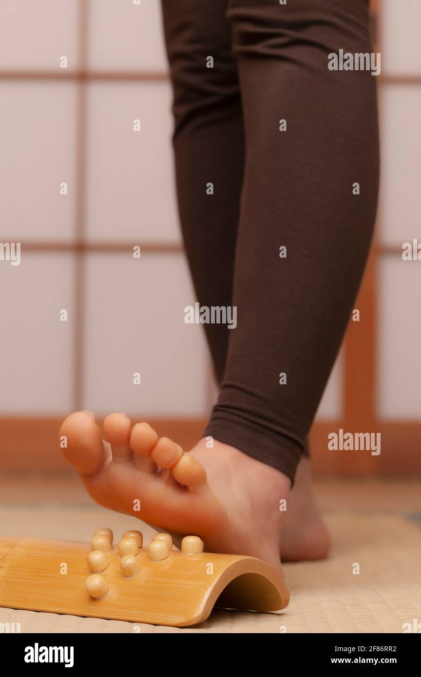 Gros plan jeune femme pieds nus utilisant un masseur pour pieds au spa Banque D'Images