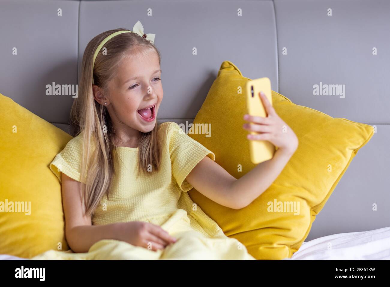 Jolie petite fille de race blanche avec cheveux blonds dans une robe  tendance couleur jaune illuminée assise à la maison pendant la quarantaine  pandémique du coronavirus et Photo Stock - Alamy