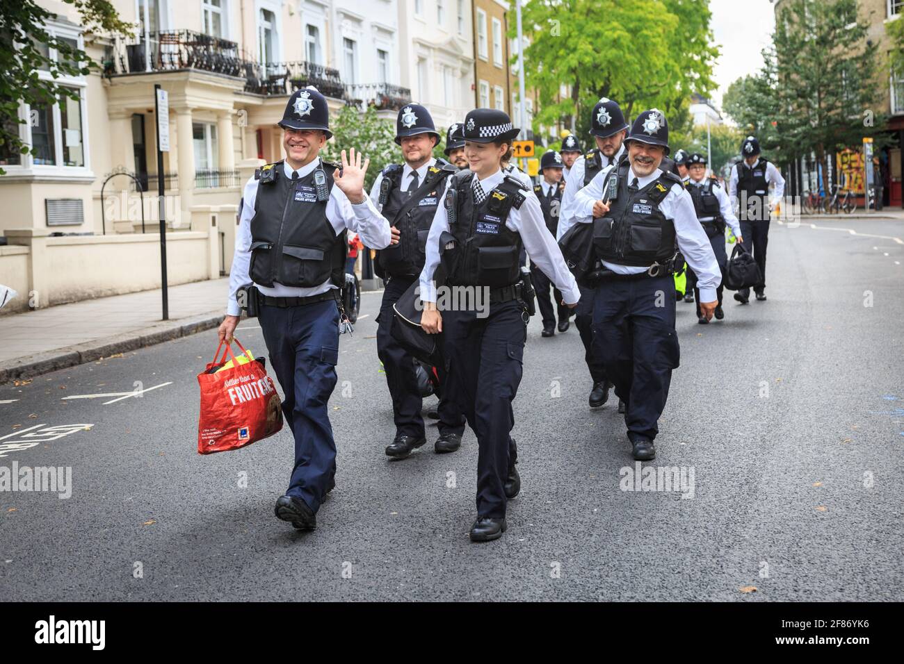 Les officiers de la police métropolitaine britannique en vestes haute viz souriant lorsqu'ils marchent jusqu'au Carnaval de Nothing Hill, Londres, Royaume-Uni Banque D'Images