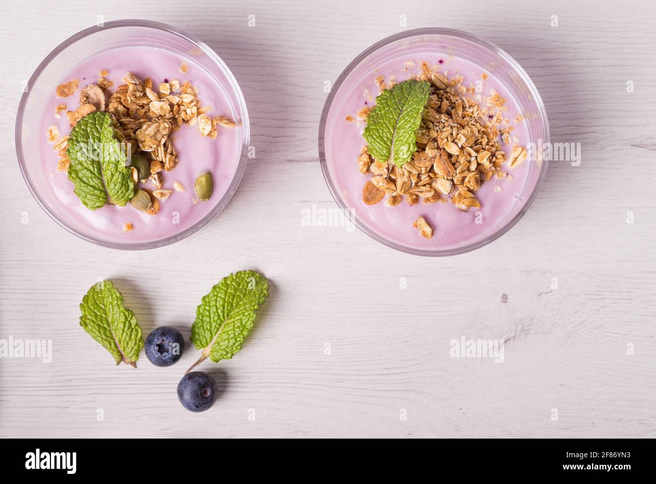 Bols de yaourt aux baies avec granola et avoine pour un petit déjeuner sain sur fond de table blanc rustique. Vue de dessus. Banque D'Images